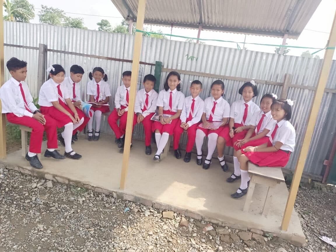 A group of students resting on a bench in the school grounds