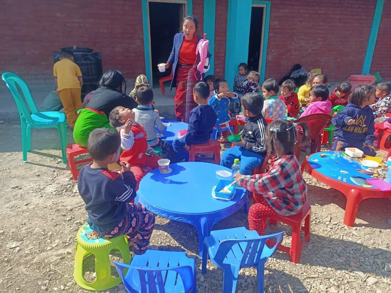 Children sharing a hot mid-day meal at brightly coloured tables
